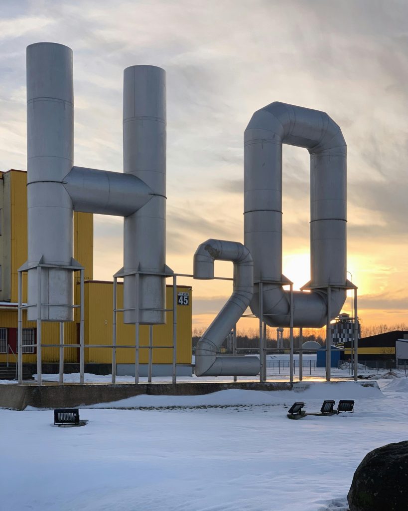 Impressive industrial plant featuring large H2O pipes at sunset. Captured in snowy Tartu, Estonia.