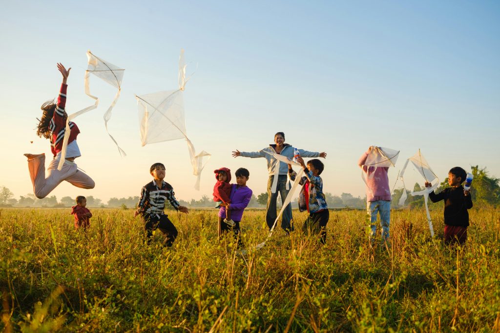 在中山南路上,跑過孩子們的明天 Joyful children flying kites in a Battambang field during sunrise, capturing a vibrant moment of play and freedom.