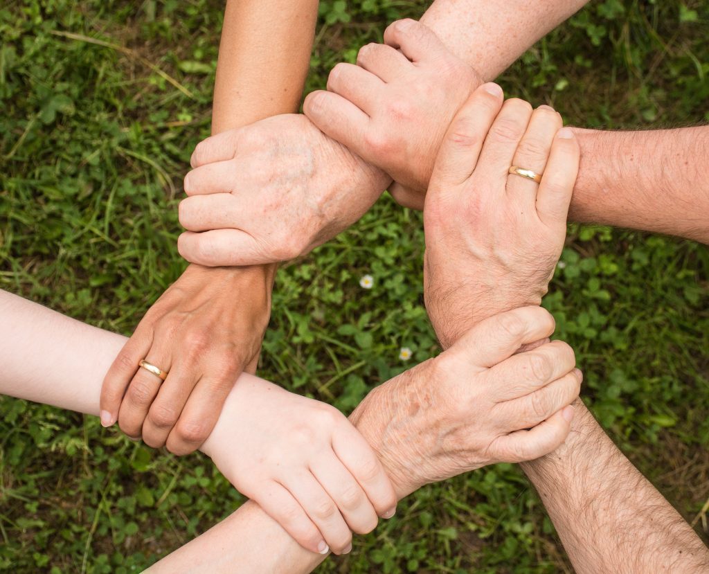 在中山南路上,跑過孩子們的明天 Close-up of diverse hands forming a connection, symbolizing teamwork and unity outdoors.