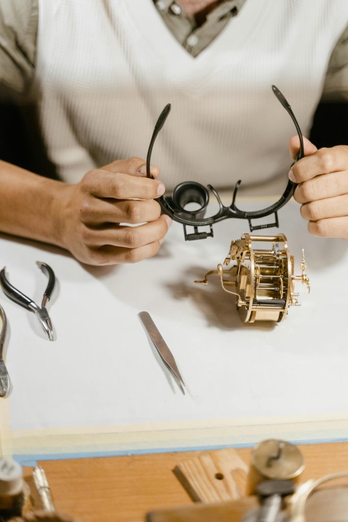 親愛的,如果控制的極致是學會放手? Close-up of a watchmaker using magnifying glasses to repair a watch mechanism.