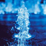 A dynamic close-up of a water fountain splash captured in vivid blue tones, showcasing motion and liquid beauty.
